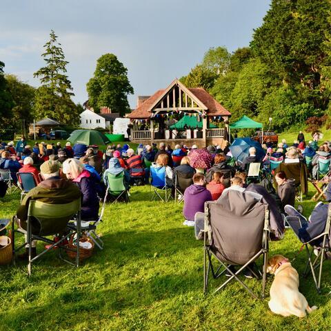 Bandstand with people sitting on camp chairs 