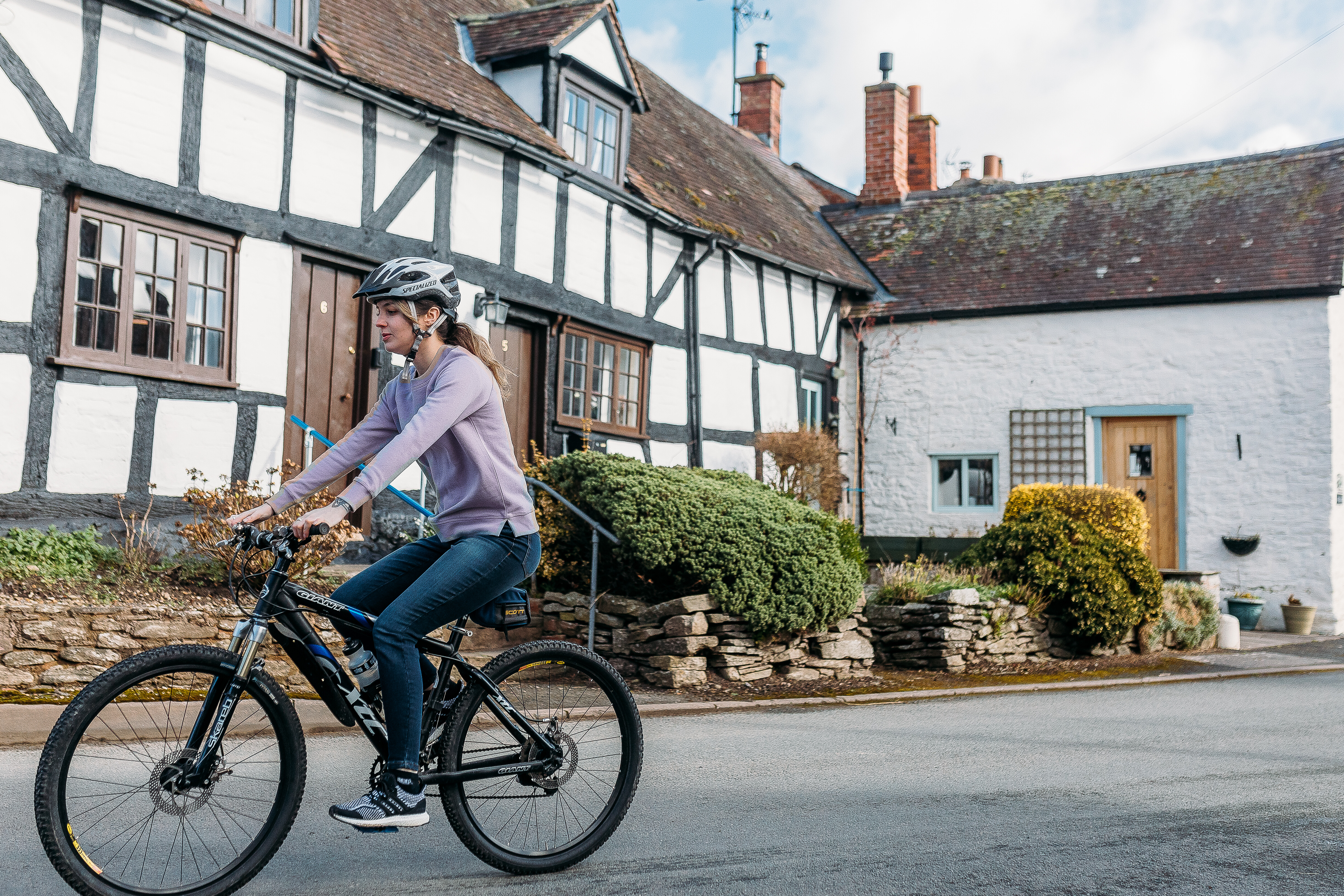 woman cycling through black and white village