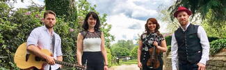 The four members of The Kilpecks standing on a country lane with their musical instruments