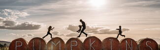 family jumping over round bales