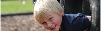 Boy poking his head through a tyre on the obstacle course