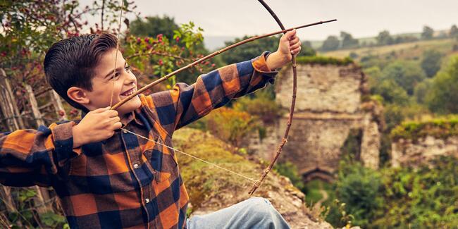 Boy shoots an arrow over castle wall