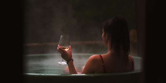 Woman holding a glass of wine in a hot tub