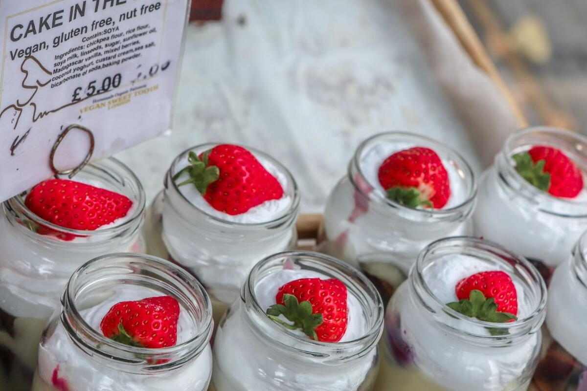 Vegan Cakes in a jar, delicous looking layers with cream and a strawberry on top