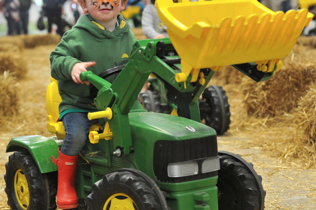 child with face paint on toy tractor