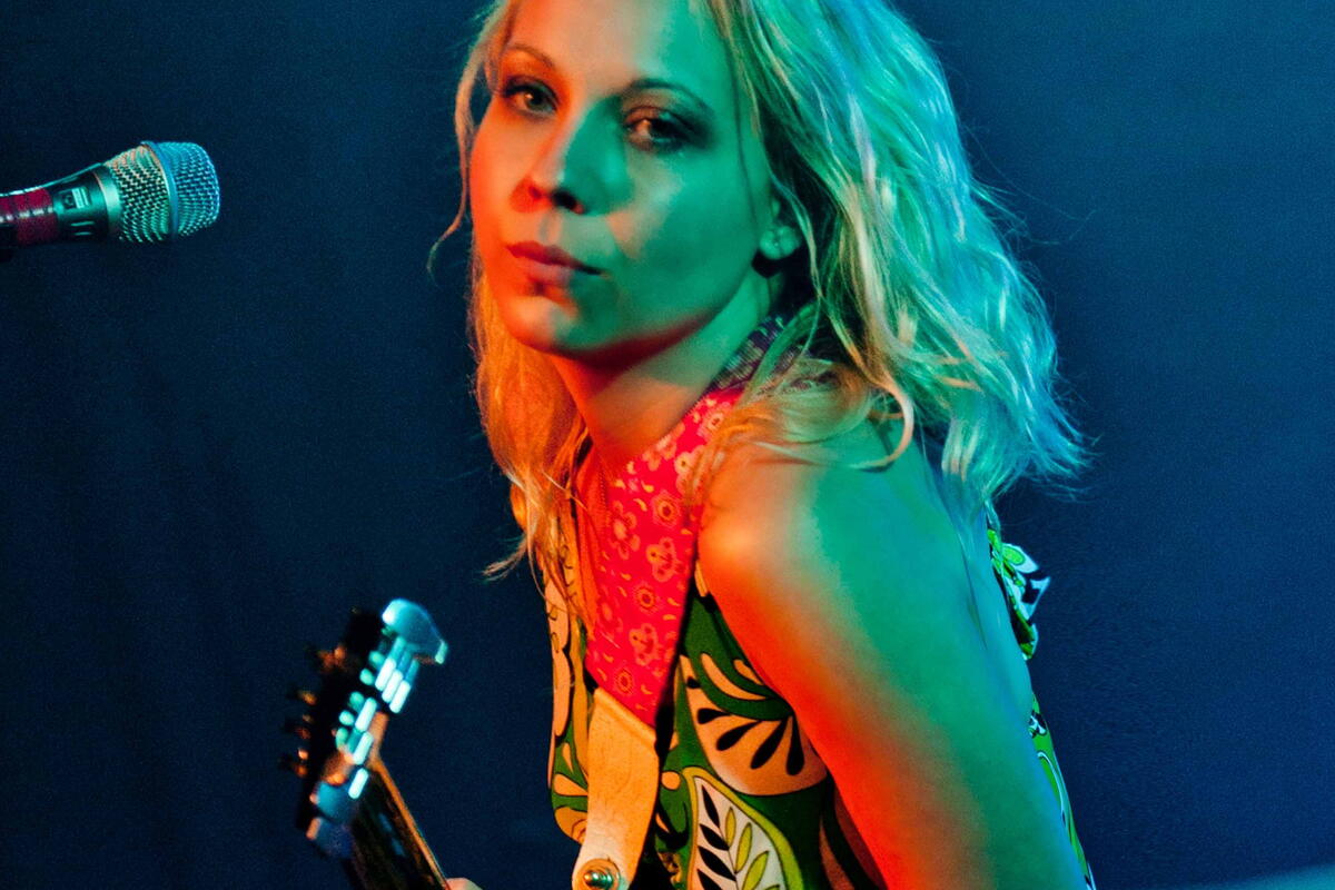 Female singer with blonde hair holding guitar 