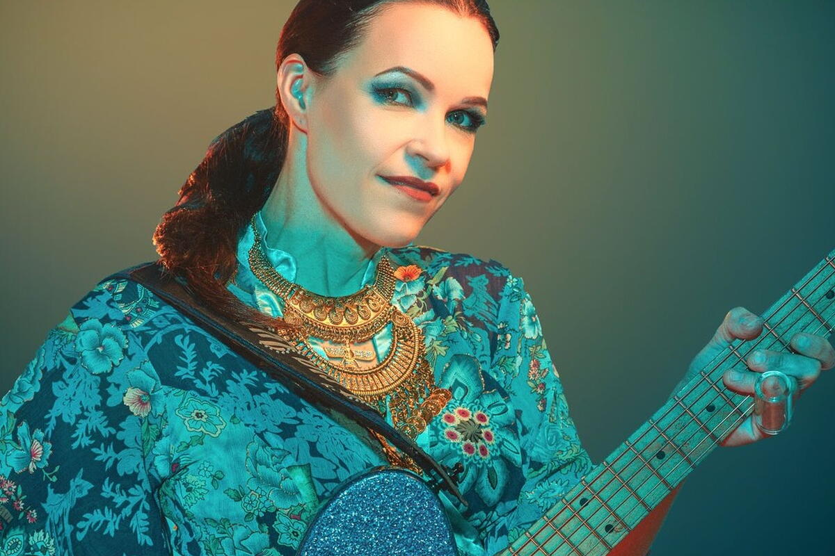 Woman with dark air dressed in blue holding guitar