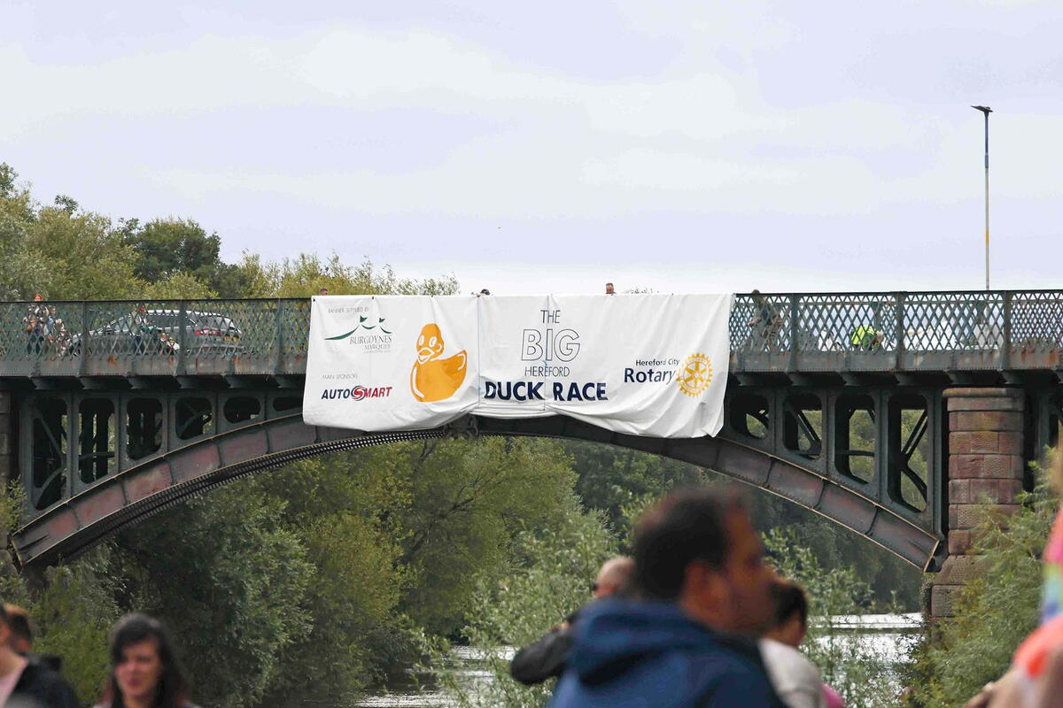 large duck race banner hanging from the side of a bridge