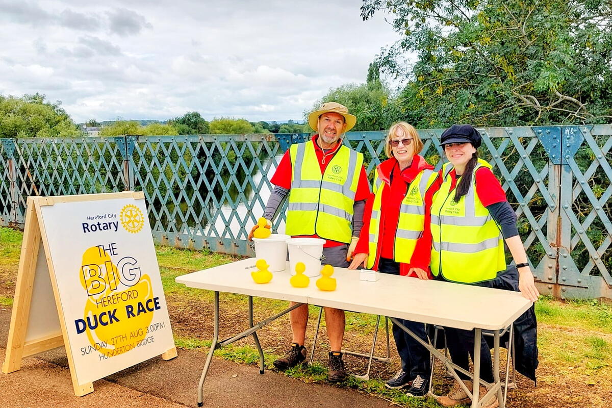 people in hi vis jackets by a trestle table outdoors 
