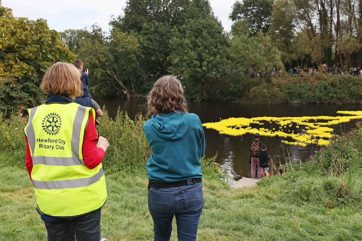 people on the banks of the rive watching the rubber duck race