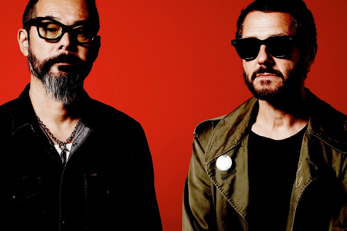 two band members in black against red background