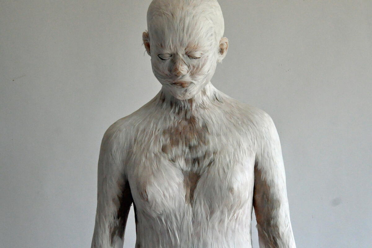 sculpture of figure with feather-like texture on surface