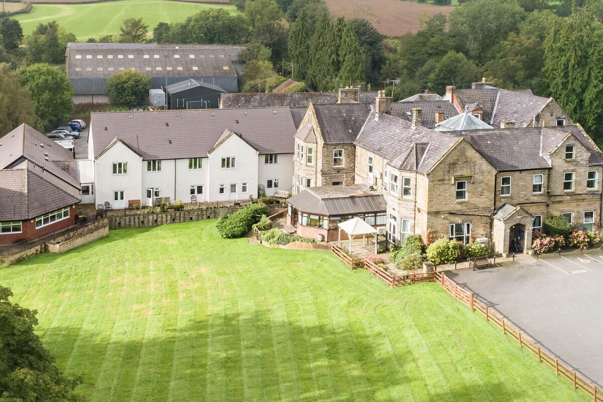 an aerial shot of a large estate of stone buildings with large lawn 