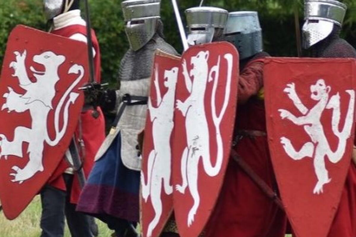 people dressed as knights in silver helmets with red shields and twin tailed lion crest