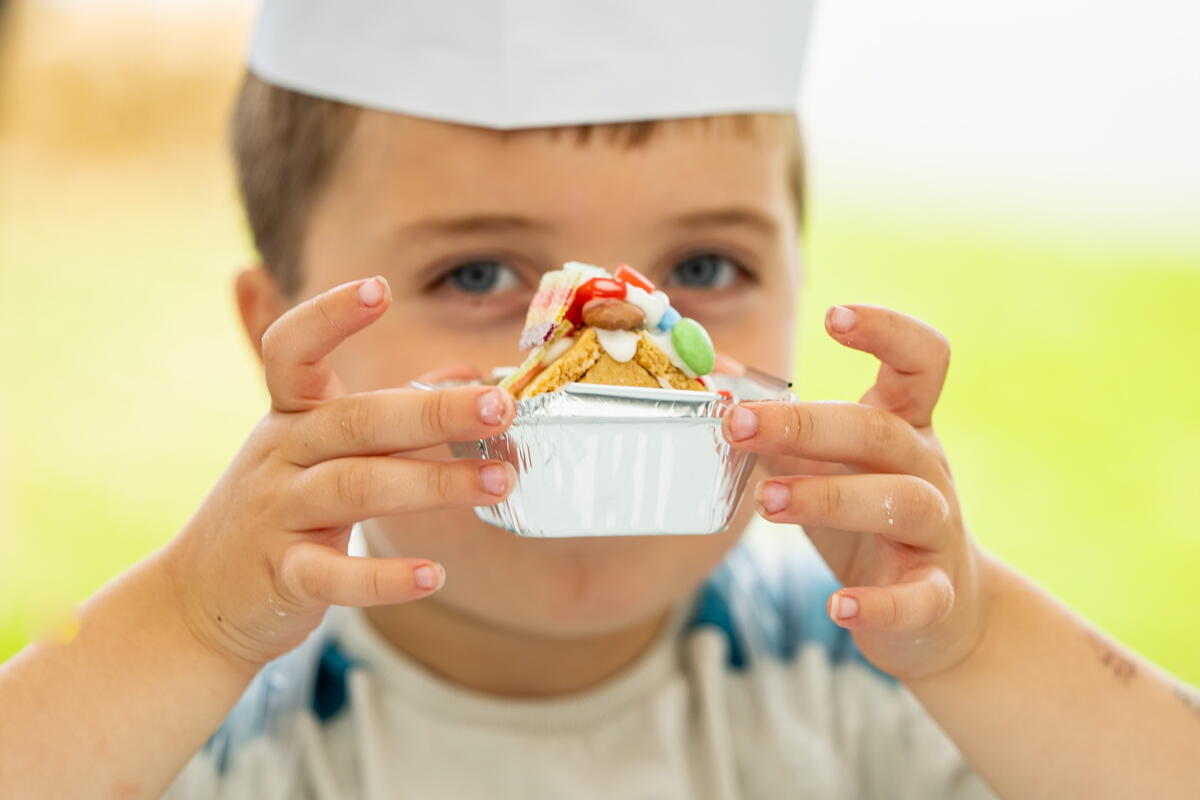 Child wearing a chefs hat holding a sweet creation