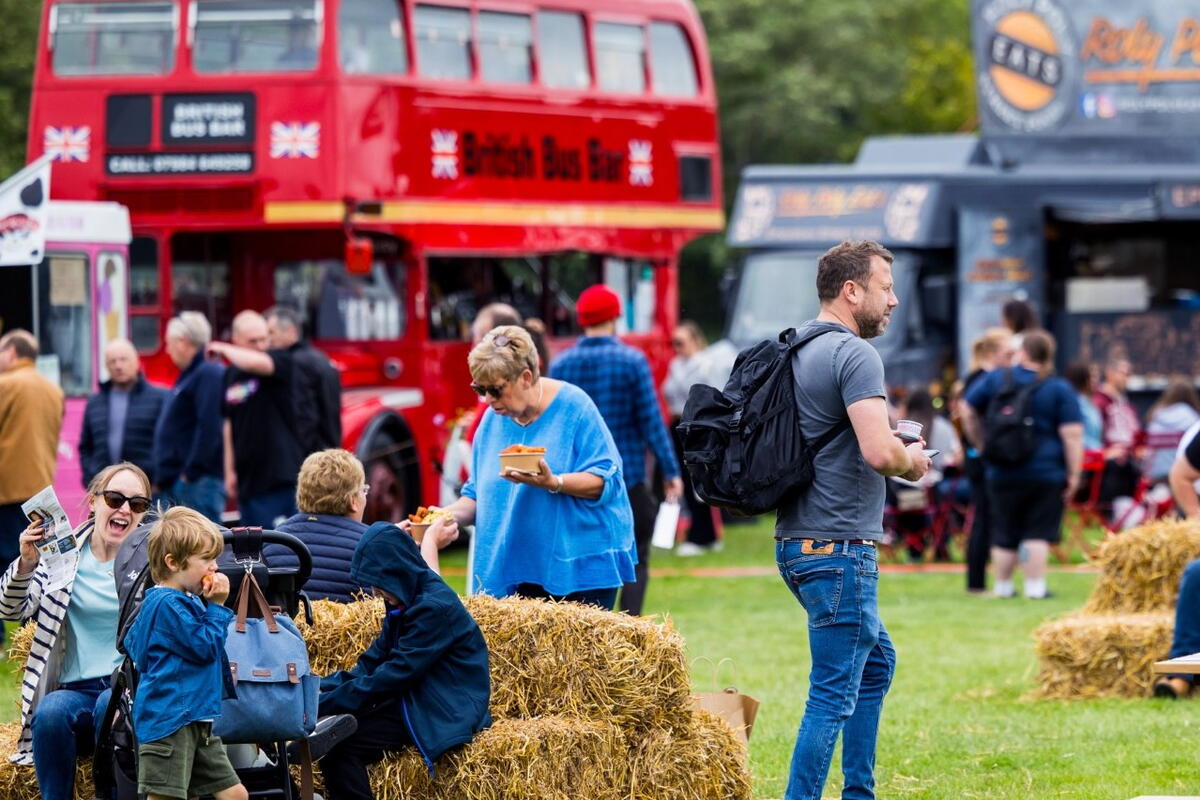 people sitting on hay bales at festival with red London bus