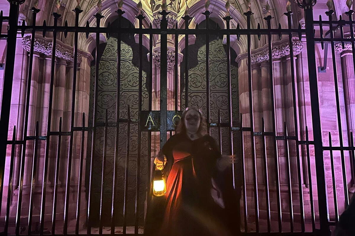 a ghost tour guide at the gates of a cathedral at night
