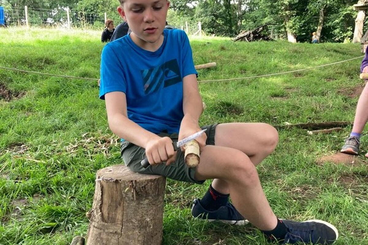 adolescent child whittling wood 