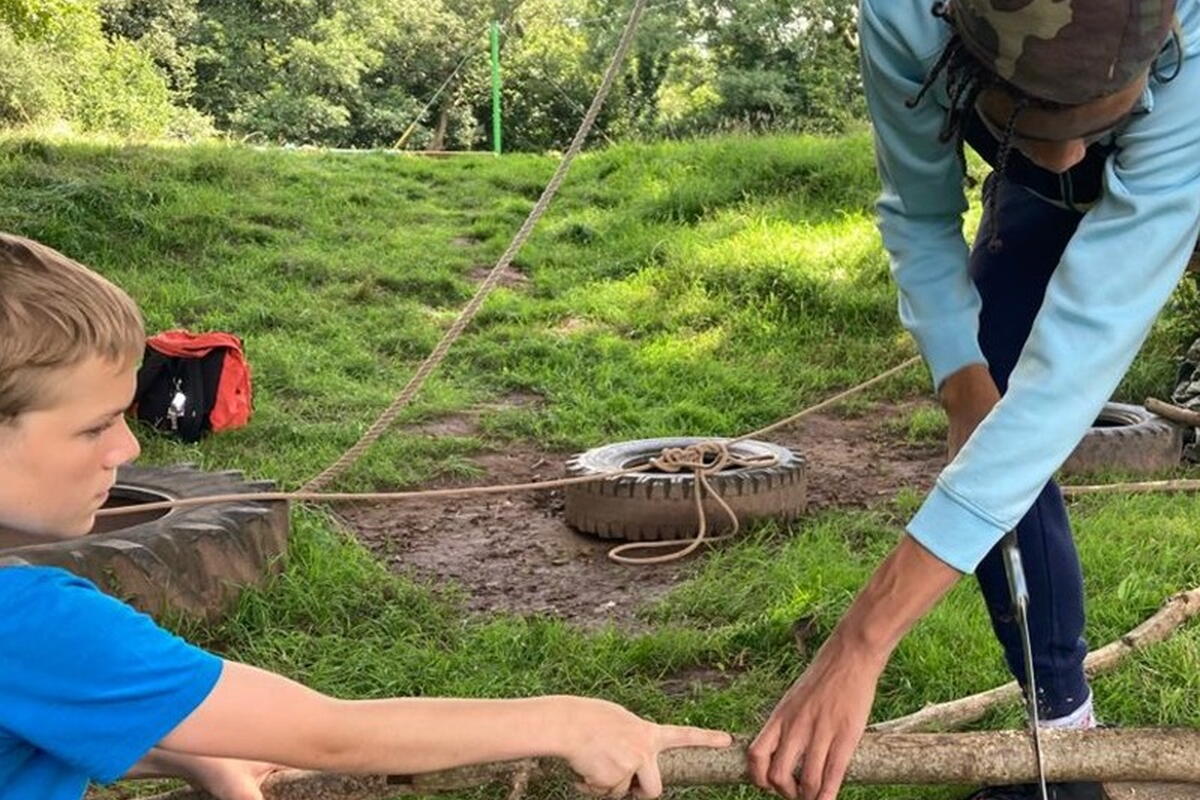 child sawing branches with help from adult