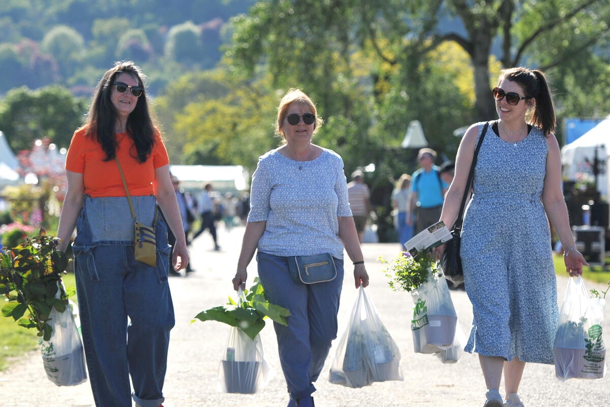People carrying shopping bags full of plants