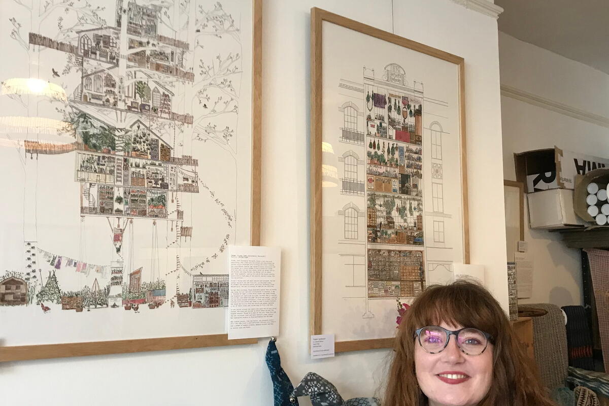 lady with glasses in front of framed artwork on the wall
