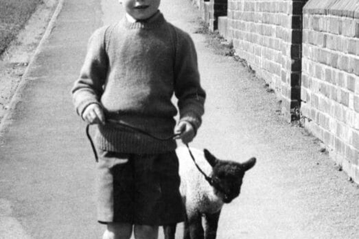 black and white image of a boy running with a lamb
