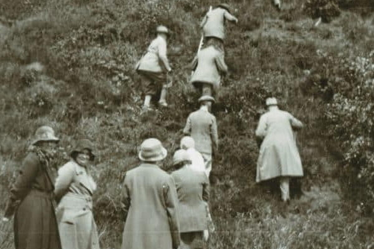 black and white image of people climbing a hill