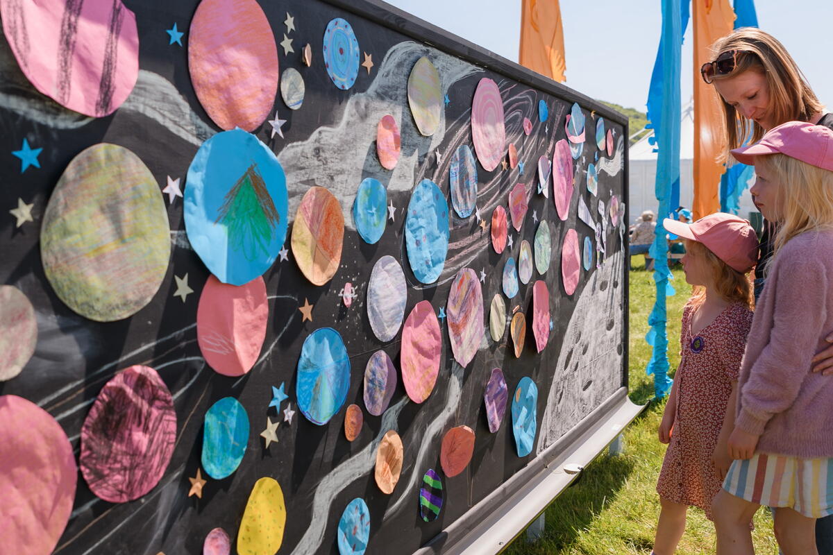 People standing in front of an art wall at a festival