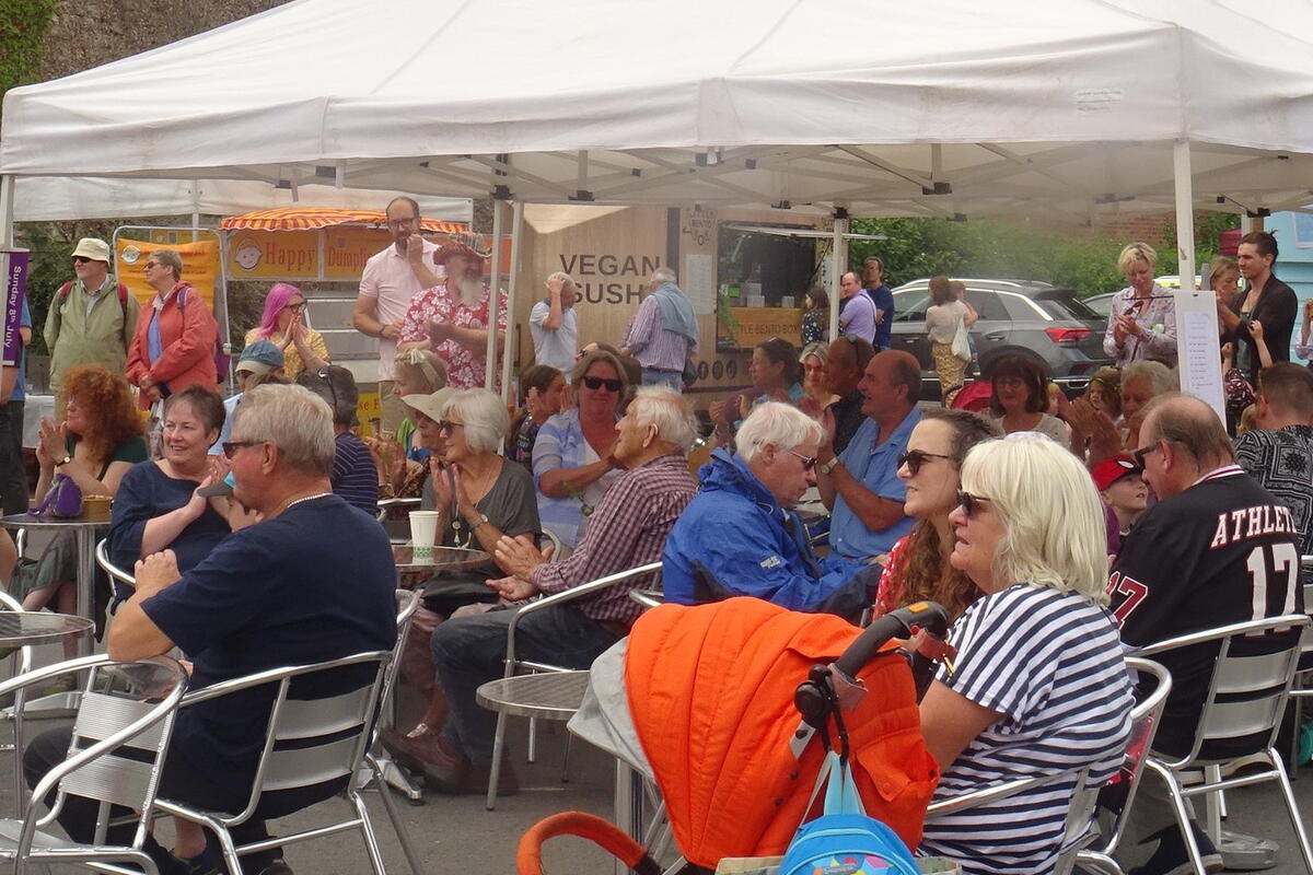 audience sat outside with a gazebo 