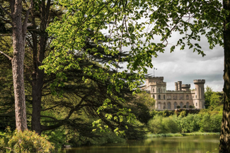 Sunny view of Eastnor Castle over the lake
