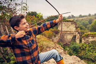 Boy shoots an arrow over castle wall