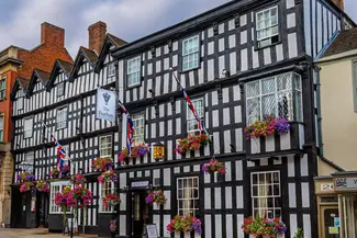 Large black and white historic hotel with hanging baskets of flowers