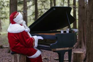 Father Christmas plays the piano in the woods