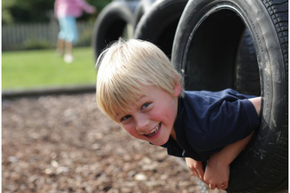 Boy poking his head through a tyre on the obstacle course