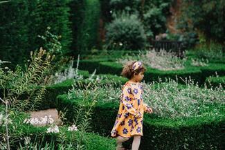 Little girl running around the flower beds at Hampton Court