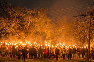 A large group of people with flame torches in an orchard for a wassailing ceremony
