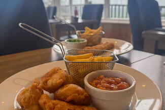 Kids chicken nuggets, chips and beans on a plate in a restaurant 