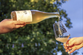 Glass of cider being pored from a bottle on sunny day 