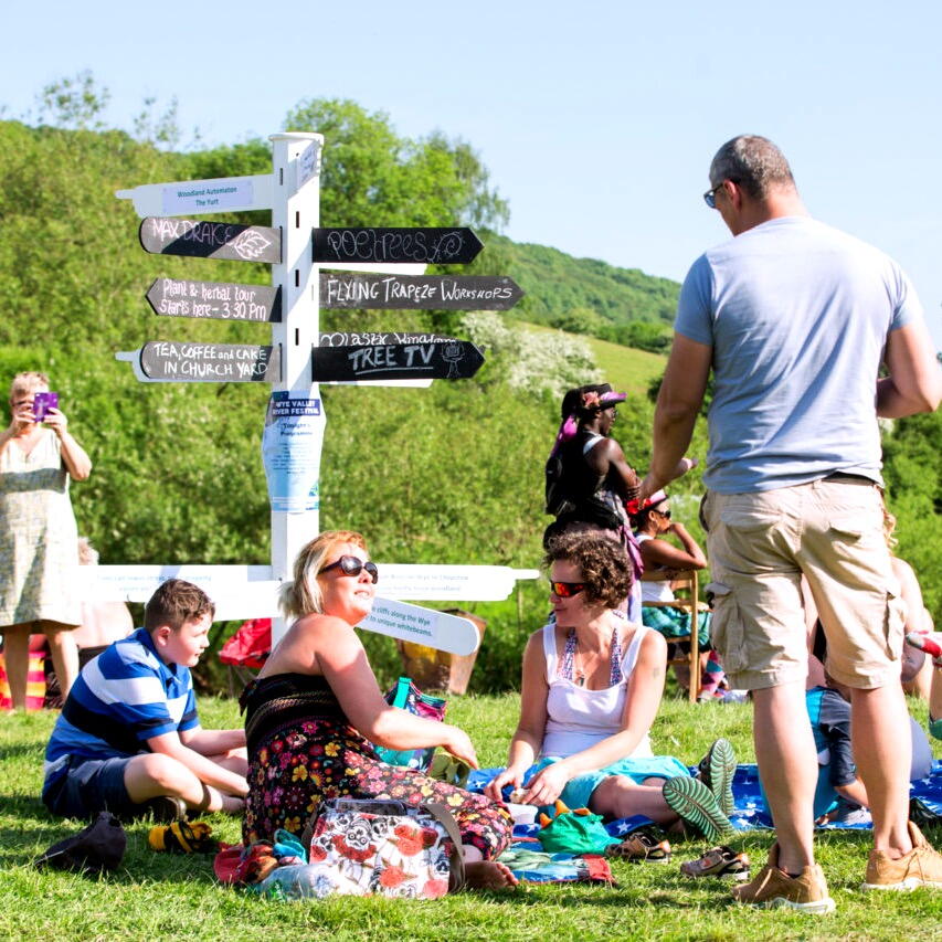 Group sit in a scenic sunny spot by the signs