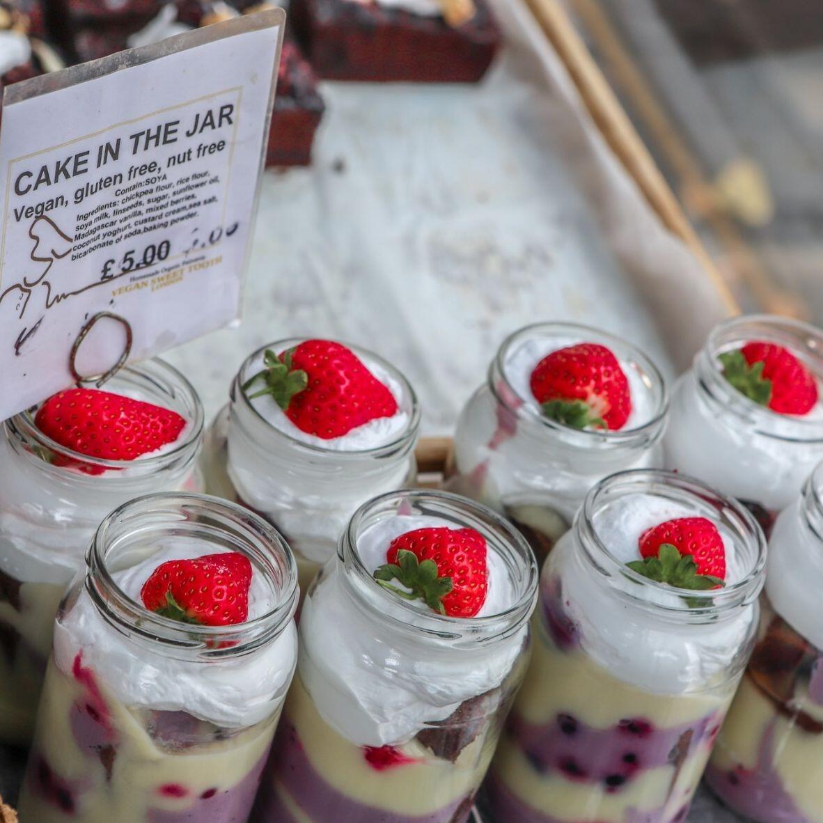 Vegan Cakes in a jar, delicous looking layers with cream and a strawberry on top