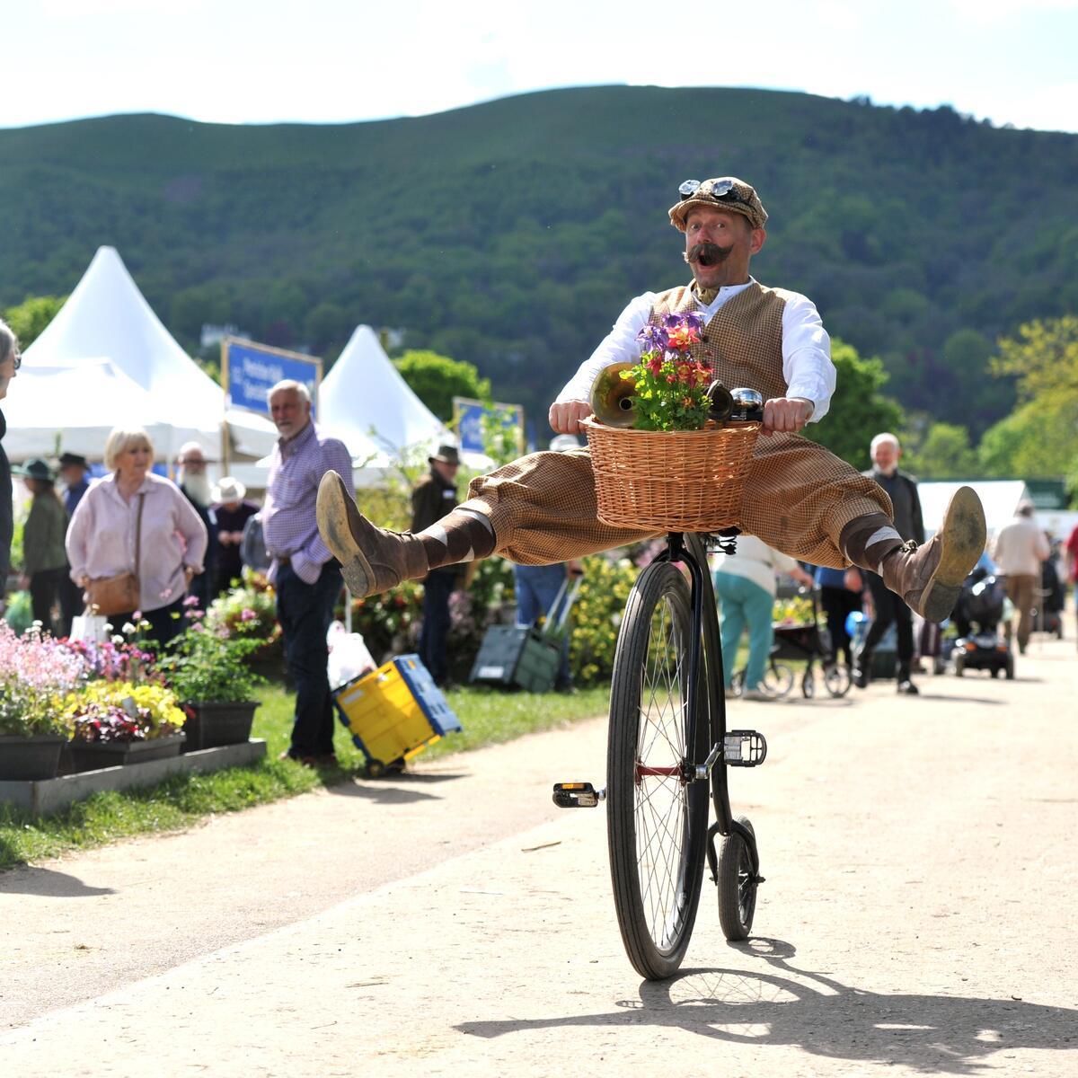 Man on a bicycle with feel in the air and flowers