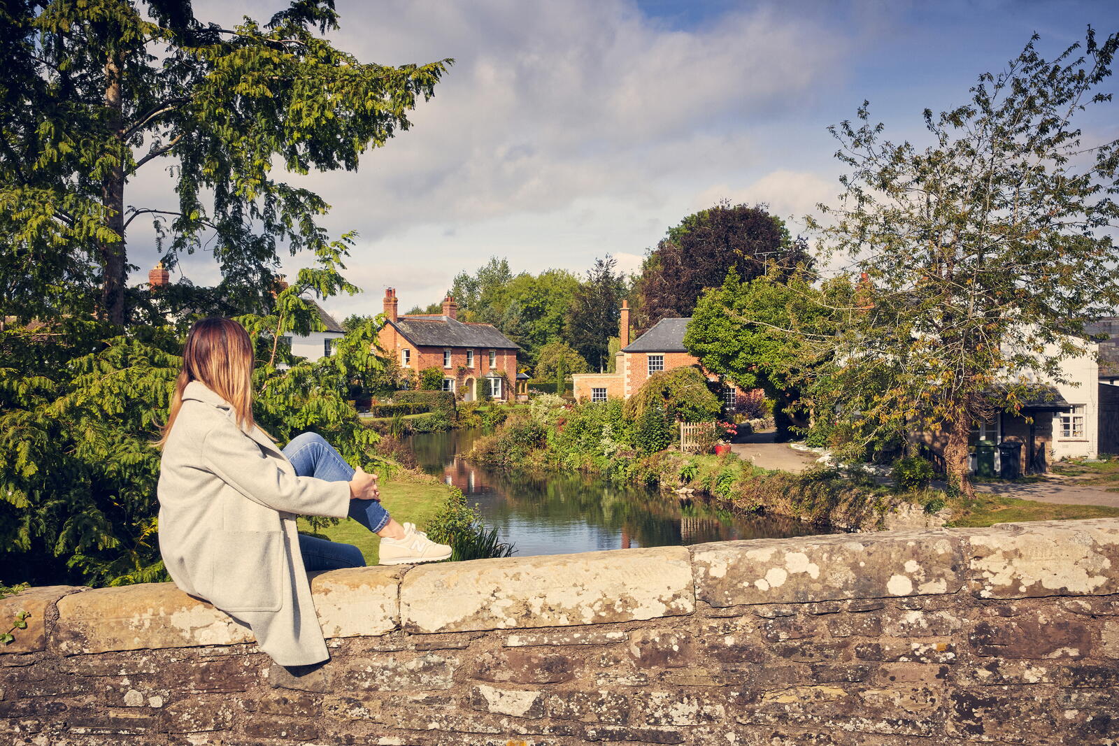 woman sitting on a bridge overlooking a river 