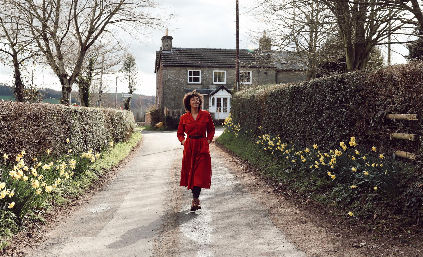A woman in a red dress walks down the lane in Kilpeck