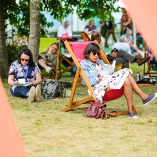 Woman reading outdoors on a deck chair 