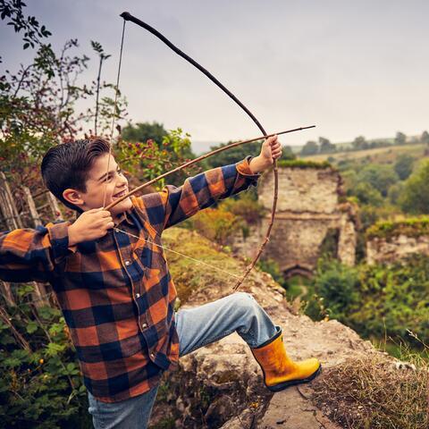 Boy shoots an arrow over castle wall