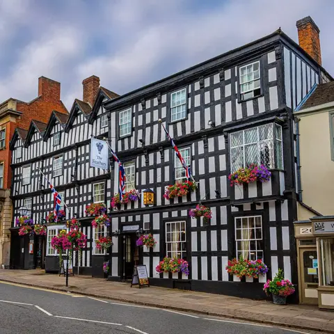 Large black and white historic hotel with hanging baskets of flowers