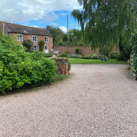 driveway leading up to a brick cottage