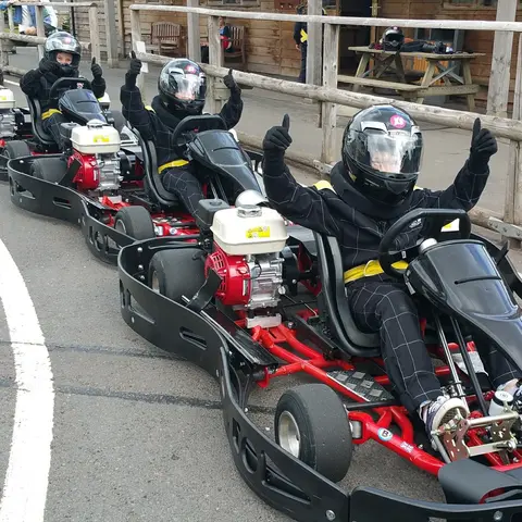 three people in go karts waiting for a race with thumbs up