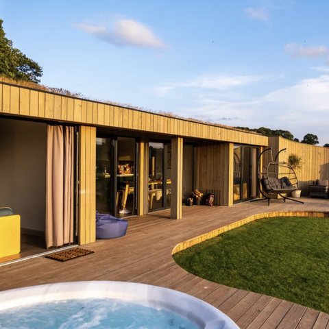 wooden lodge with blue sky and hot tub in foreground 