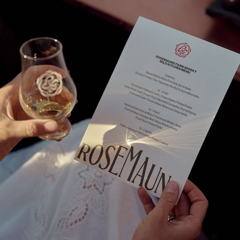 woman holding whiskey glass and menu in dappled sunlight